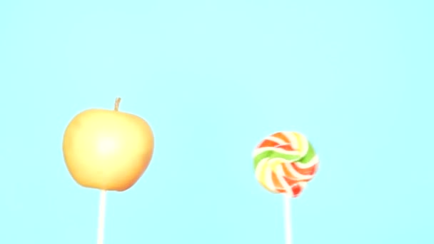 Begreppet hälsosam och ohälsosam mat. Äpple mot en godis på en klarblå bakgrund — Stockvideo