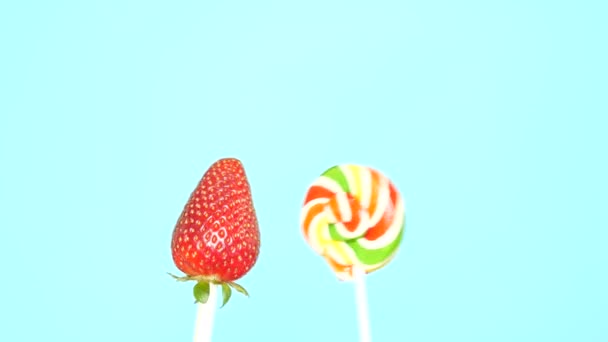 Concept of healthy and unhealthy food. strawberry against candy on a bright blue background — Stock Video