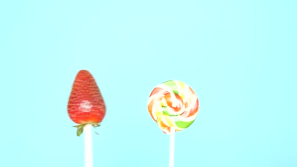 건강하고 건강에 해로운 음식의 개념. 밝은 파란색 배경에 사탕에 대한 딸기 — 비디오