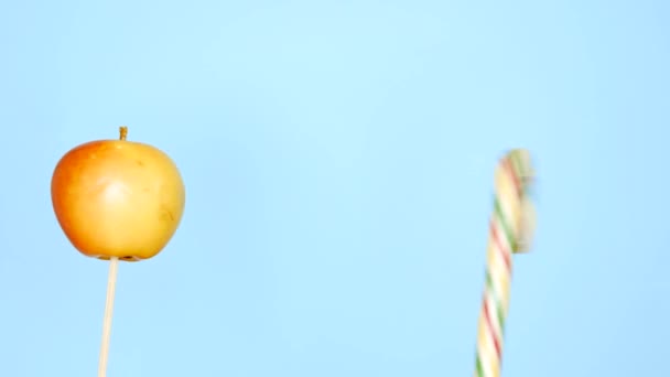 健康的で不健康な食べ物の概念。明るい青い背景にキャンディーに対するアップル — ストック動画