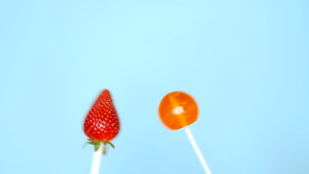Έννοια του υγιεινού και ανθυγιεινά τρόφιμα. φράουλα κατά της καραμέλας σε ένα φωτεινό μπλε φόντο — Αρχείο Βίντεο