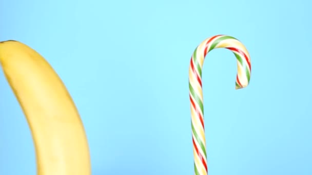 Концепция здоровой и нездоровой пищи. банан против конфет на ярко-голубом фоне . — стоковое видео
