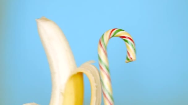 Begreppet hälsosam och ohälsosam mat. banan mot godis på en klarblå bakgrund. — Stockvideo