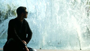 Fıskiyenin yanında dinlenen bir adamın silueti