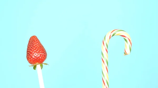 Konzept der gesunden und ungesunden Ernährung. Erdbeere gegen Bonbons auf hellblauem Hintergrund — Stockfoto