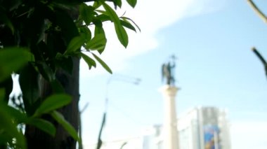 yeşillik çerçevesinde mavi gökyüzüne karşı bir kılıç ile bir melek bulanık siluet heykeli