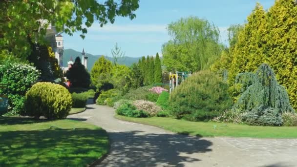 Luxe hotel in Victoriaanse stijl, ondergedompeld in prachtige bomen en struiken. daken met Spiers op een achtergrond van helder blauwe hemel — Stockvideo