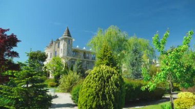 Viktorya tarzında lüks otel, güzel ağaçlar ve çalılar dalmış. berrak mavi gökyüzü bir arka plan üzerinde spiers ile çatılar