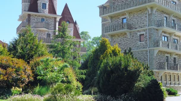 Lussuoso hotel in stile vittoriano, immerso in splendidi alberi e cespugli. tetti con guglie su uno sfondo di cielo azzurro chiaro — Video Stock