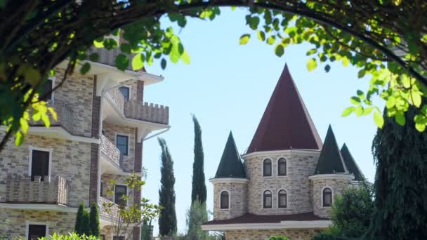 Lussuoso hotel in stile vittoriano, immerso in splendidi alberi e cespugli. tetti con guglie su uno sfondo di cielo azzurro chiaro — Video Stock