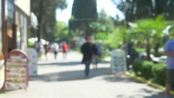 Αποεπικεντρωμένο φόντο. ηλιόλουστο καλοκαιρινό πάρκο με άτομα που περπατούν — Αρχείο Βίντεο
