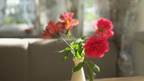 Close-up. Schattig boeket van rode rozen en Freesia in een vaas op een tafel op een zonnige zomerdag in een café — Stockvideo