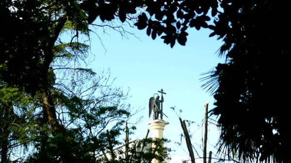 Розмита силуетна статуя ангела з мечем на блакитне небо в рамі листя — стокове фото