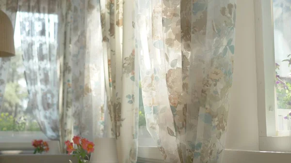 Představa rána. z polootevřeného okna mával ve větru nádherné záclony s květinovým tiskem. sluneční záře na oknech — Stock fotografie