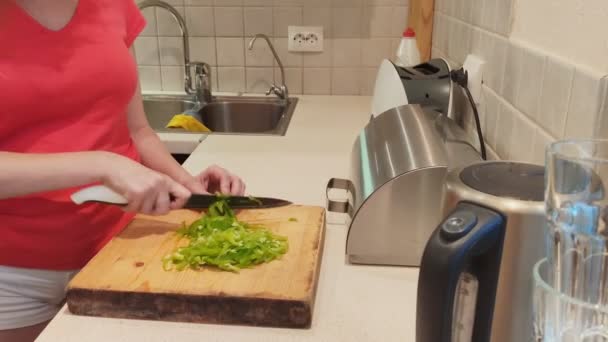 Primo piano. donna taglia paprica verde su tavola di legno a casa cucina — Video Stock