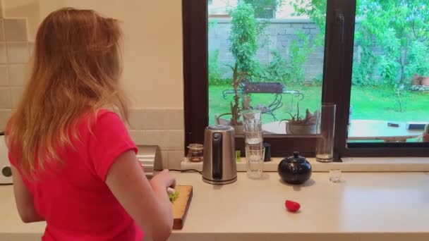Frau schneidet in der heimischen Küche grünen Paprika auf Holzbrett — Stockvideo