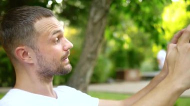 Close. Bir adam blogcu bir park bankında otururken bir akıllı telefon kullanır. Birisiyle görüntülü görüşmesi var.