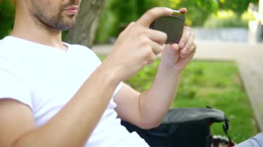 Close. Bir adam blogcu bir park bankında otururken bir akıllı telefon kullanır. Birisiyle görüntülü görüşmesi var.