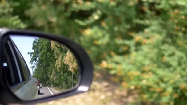 Concepto de viaje o transporte de tráfico. Espejo retrovisor que refleja la línea de coches en la carretera en el campo mientras conduce — Vídeo de stock