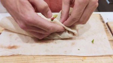 Close. mens eller shawarma hazırlanıyor. Et, sebze ve ekşi krema ile lezzetli shawarma pişirme süreci. ahşap kesme tahtası üzerinde