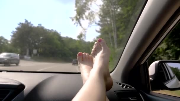 Concepto de viaje con comodidad piernas femeninas en el panel del coche. Ventana y patas femeninas con pedicura de cerca sobre el fondo de la ruta del coche — Vídeos de Stock