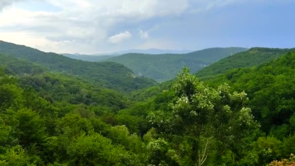 Horské pásmo s viditelnými siluety píků, které se objevují mlhou proti modré obloze a bílým mračen — Stock video