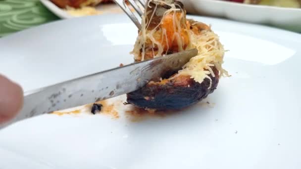 Alguien corta un trozo de hongo horneado con un tenedor y un cuchillo — Vídeo de stock