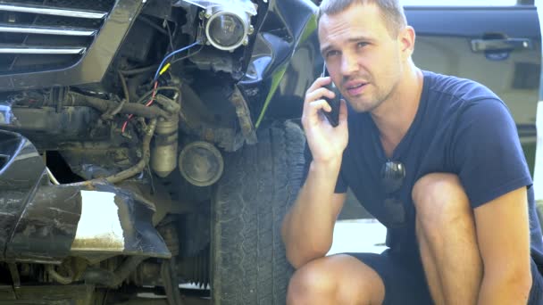 Concepto de accidente de coche. conductor masculino hace llamadas telefónicas después de un accidente de tráfico sentado junto a un parachoques de coche roto — Vídeos de Stock