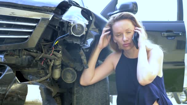 Auto-ongeval concept. Vrouwelijke bestuurder doet telefoontjes na een verkeersongeval zittend door een gebroken auto bumper — Stockvideo