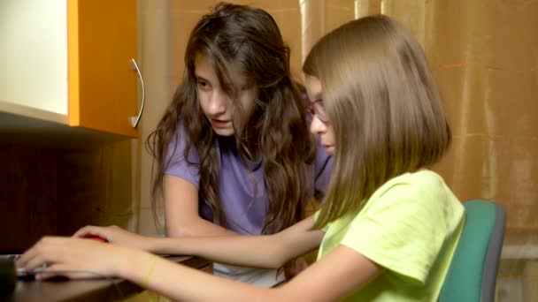 Две девушки подруги, подростки студенты сидят вместе за тренировочным столом и используют ноутбук в вечернее время. они веселы и счастливы — стоковое видео