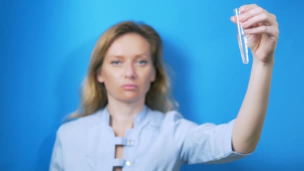 Conceito de FIV. O embriologista tem um tubo de ensaio na mão. no fundo azul — Vídeo de Stock