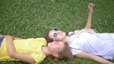 yaz tatil kavramı. Yukarıdan görüntüle. İki sevimli neşeli genç kız güneş gözlüğü birlikte yeşil çim yatıyor. Yaz güneşli gün.