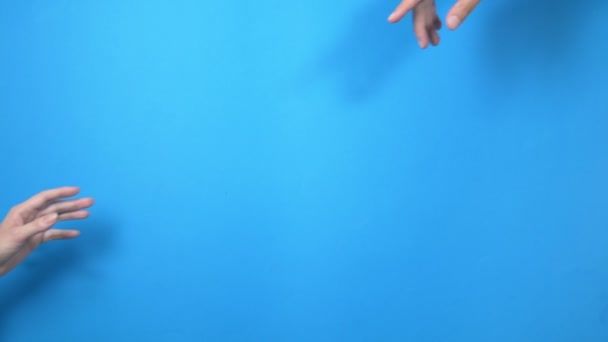 Två manliga och kvinnliga händer nå ut till varandra, nästan rörande, på en blå bakgrund — Stockvideo