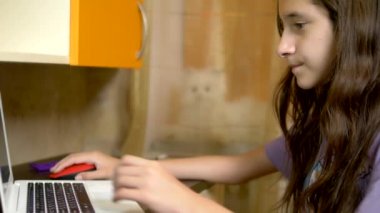 öğrenci kız Genç odasında bir masada oturan beyaz bir dizüstü bilgisayar ile hat üzerinde öğrenme. akşam saatinde