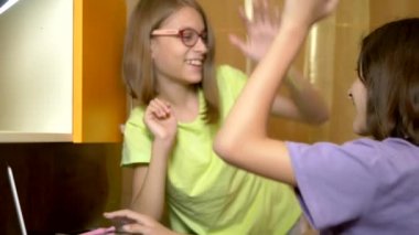 İki kız kız, gençler öğrenciler birlikte eğitim masasında oturmak ve akşam bir laptop kullanın. Onlar neşeli ve mutlu