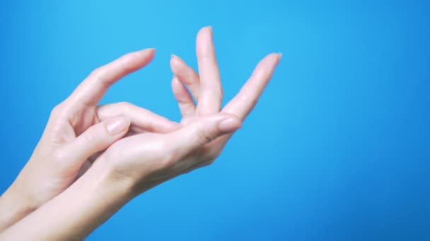 Ніжні жіночі руки з природним манікюром красиво рухаються на синьому фоні. Місце для тексту . — стокове відео