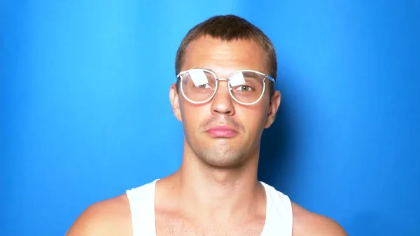 Mavi bir arka plan üzerinde pembe gözlük yakışıklı eğlenceli adam, dans ve komik yüzler yapma. Portre. kopyalama alanı — Stok fotoğraf