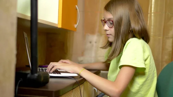 Uczeń dziewczyna uczenia się na linii z białym laptopem siedzi przy stole w jej teen pokoju. w porze wieczornej — Zdjęcie stockowe
