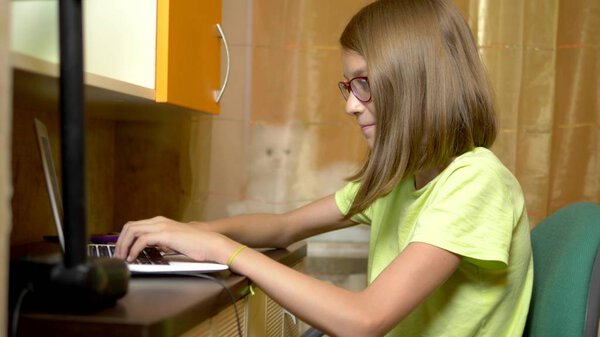 студентка учится онлайн с белым ноутбуком, сидящим за столом в ее комнате для подростков. вечернее время
