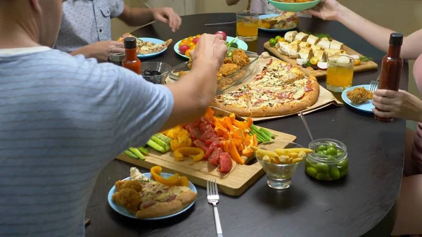 La famiglia mangia in un ambiente domestico accogliente. Cibo fatto in casa, pizza fatta in casa. Felice famiglia che pranza insieme seduti alla tavola abbondantemente apparecchiata — Foto Stock