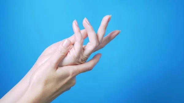 Las manos tiernas femeninas con la manicura natural se mueven hermosamente sobre el fondo azul. Lugar para el texto . — Foto de Stock