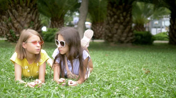 Dos chicas lindas relajarse en el parque en la hierba —  Fotos de Stock