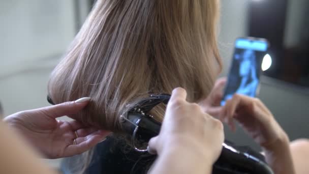 Close-up. Professional hairdresser using curling iron. Hair curls in salon, — Stock Video