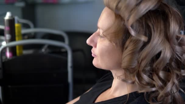 Close-up. Professional hairdresser using curling iron. Hair curls in salon, — Stock Video