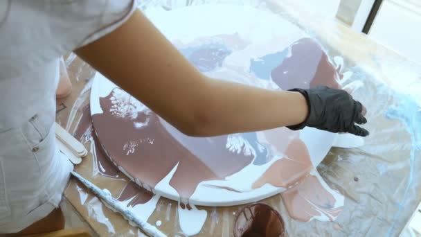 Close-up. ženské ruce v černých gumových rukavicích vytvářejí obrázek s akrylicovými. Proces laku s akrylovým uměním. Nalévání akrylové barvy na kruhové plátno . — Stock video