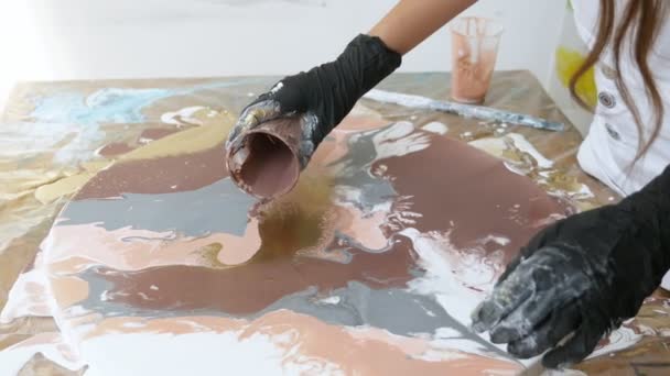 Primer plano. manos femeninas en guantes de goma negro crea una imagen con acrílicos. Proceso de pintura acrílica de arte fluido. Verter pintura acrílica en el círculo de lona  . — Vídeo de stock