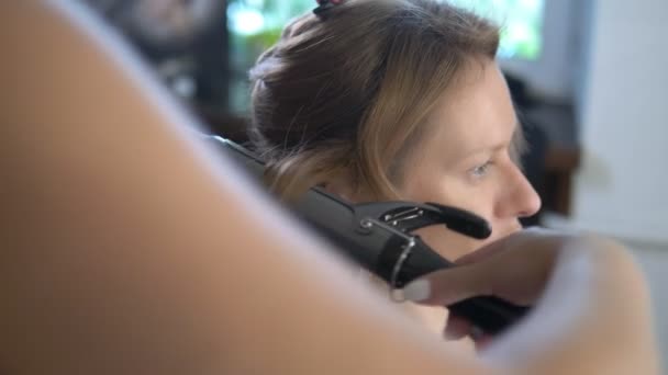 Close-up. Professional hairdresser using curling iron. Hair curls in salon, — Stock Video