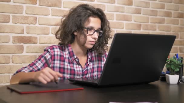 Ci siamo quasi. adolescente con i capelli ricci bruna, in una camicia a quadri funziona su un tablet grafico utilizzando uno stilo — Video Stock