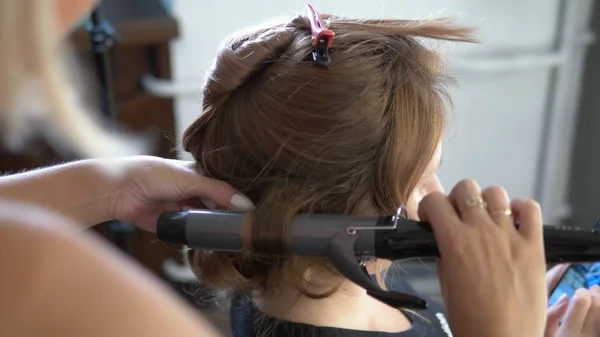 Close-up. Professional hairdresser using curling iron. Hair curls in salon, — Stock Photo, Image