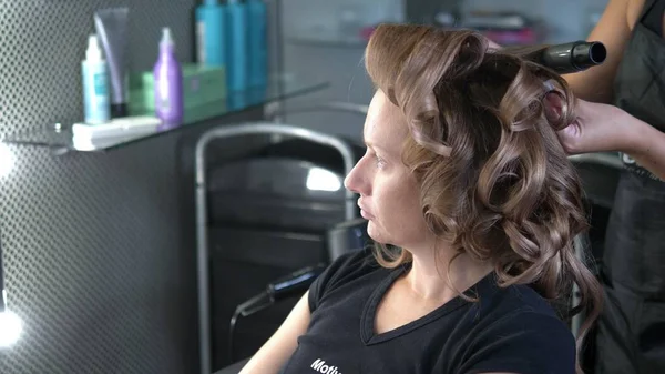 Close-up. Professional hairdresser using curling iron. Hair curls in salon, — Stock Photo, Image